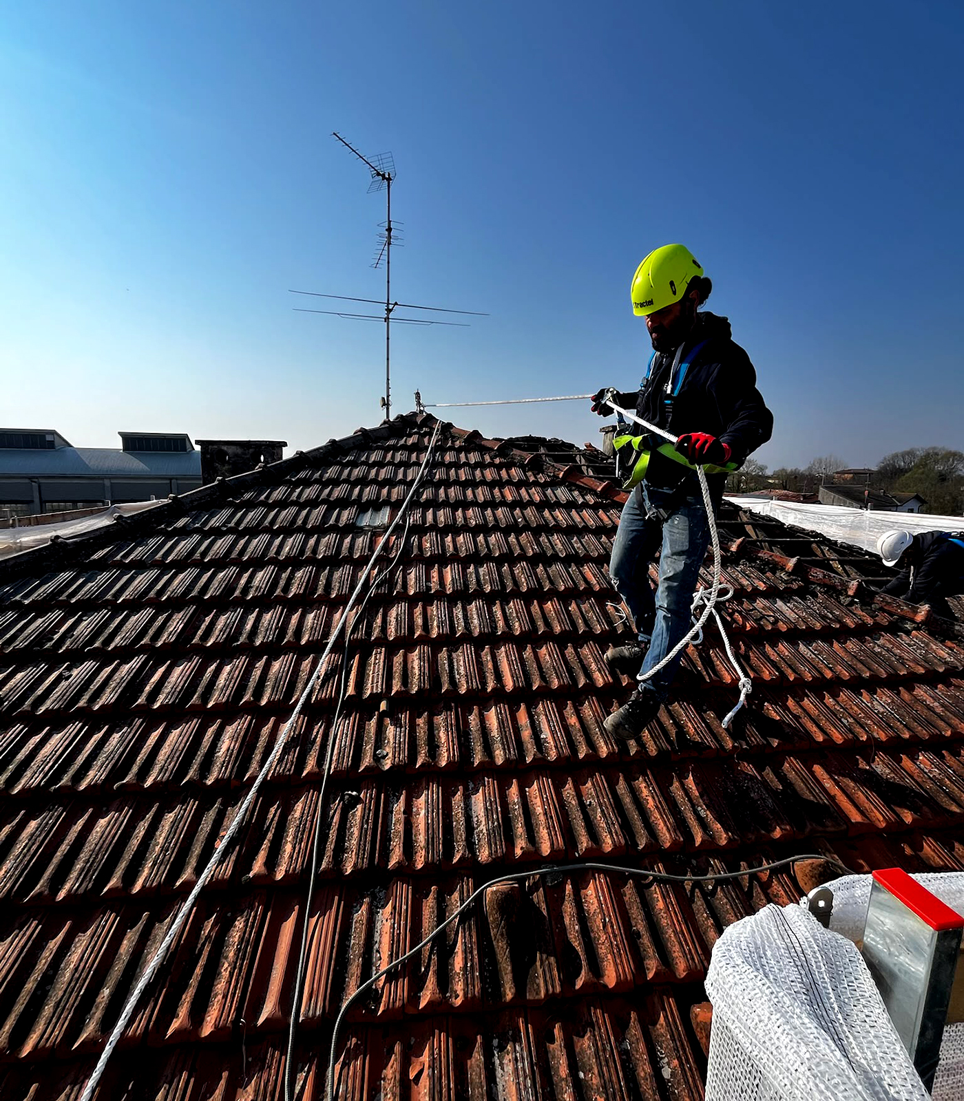 Operatore GE&CO con imbracatura durante la manutenzione di un tetto in tegole a Pavia